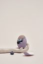 Healthy sweet blueberries in cracked painted eggshell placed on clay hand against white background