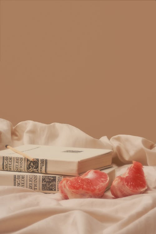 Free Sour grapefruit placed near books on creased fabric Stock Photo