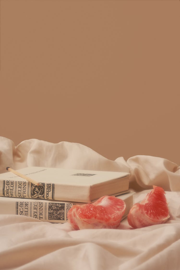 Sour Grapefruit Placed Near Books On Creased Fabric