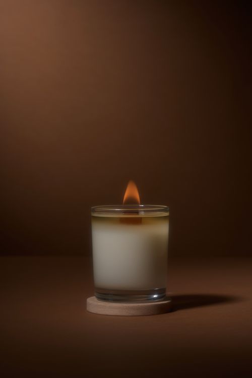 Free Aroma candle with hot burning flame casting shadow on brown table in studio Stock Photo