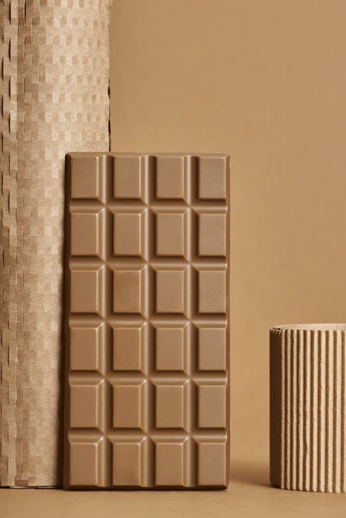 Free Sweet chocolate bar for dessert placed near cardboard in studio against light brown background Stock Photo
