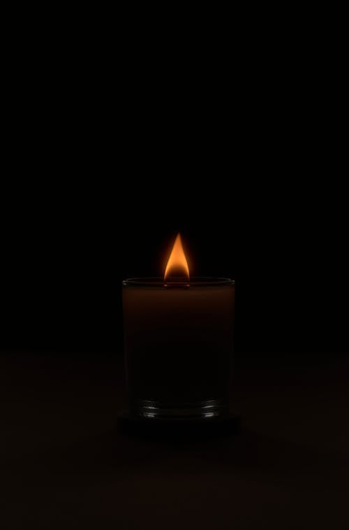 Flaming candle in dark obscure studio