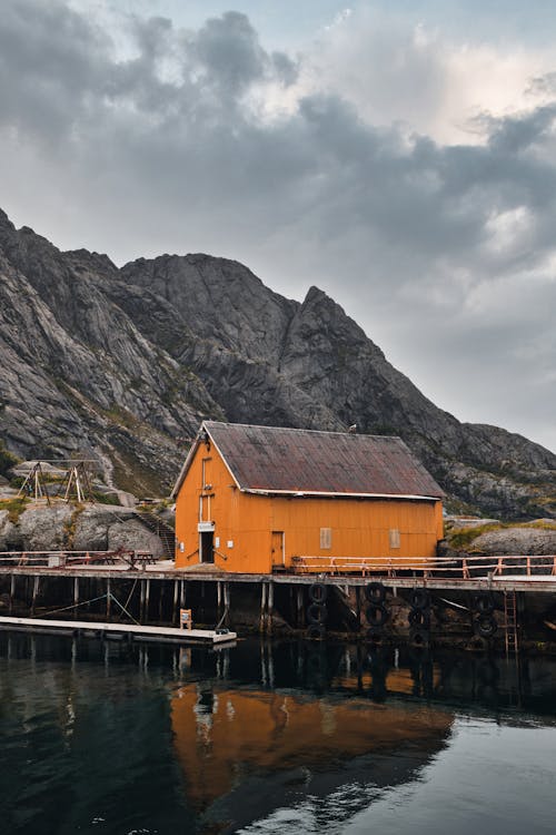 Brown Wooden House on Dock Near Mountain