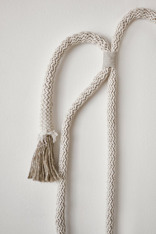 Texture of curved tied rope for minimalist decor hanging on white wall in light room