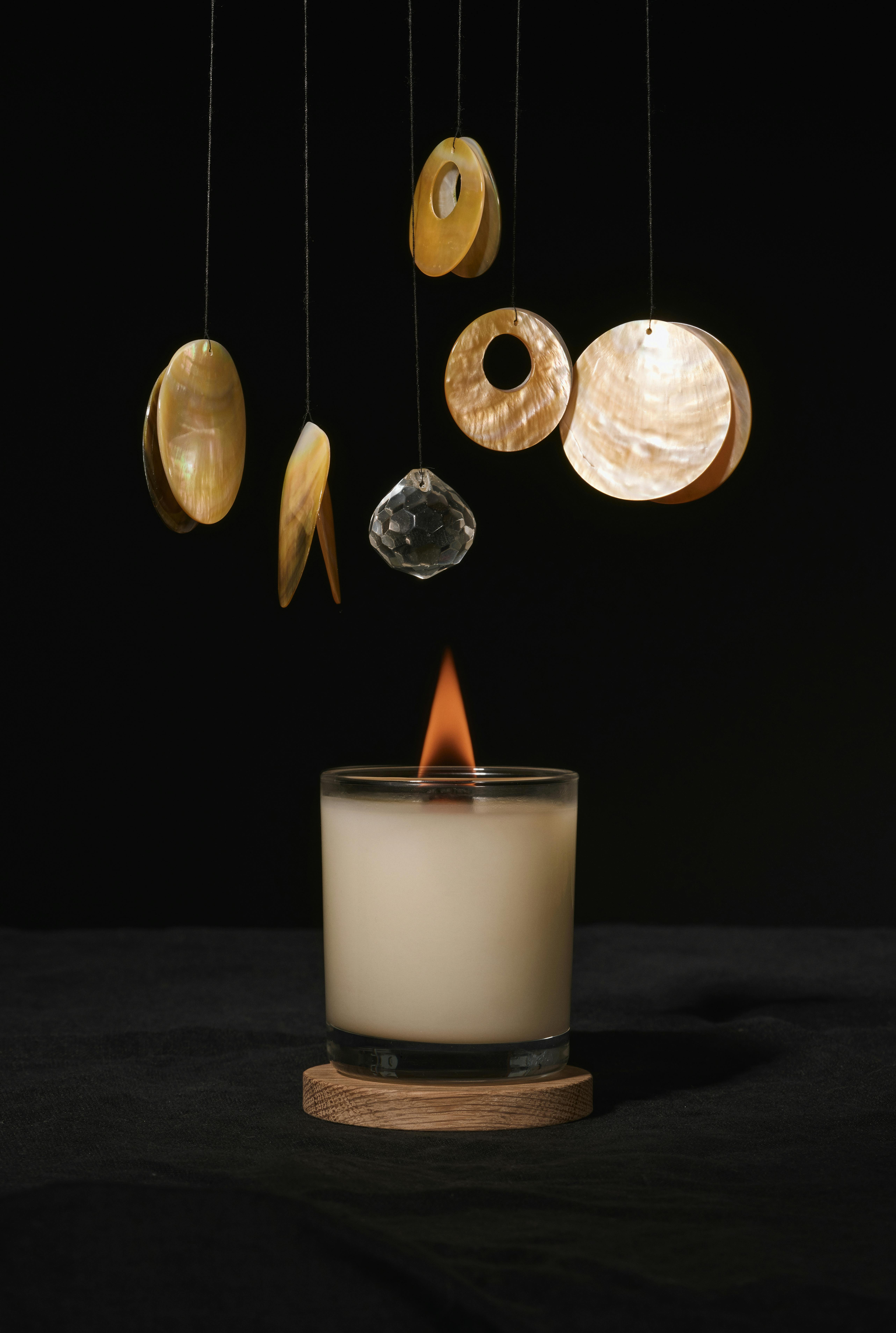 flaming candle under hanging decor in dark room