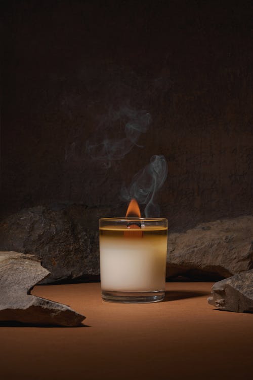 Burning fuming candle placed near boulders