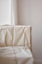 Big boxes wrapped in white cloth and tied with rope placed near white wall and curtain