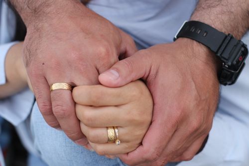 Free Intimate close-up of two hands with gold wedding rings and a wristwatch. Stock Photo