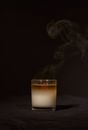 Wax aroma candle in transparent glass holder with smoke placed against black background