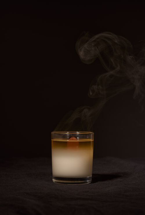 Free Wax aroma candle in transparent glass holder with smoke placed against black background Stock Photo