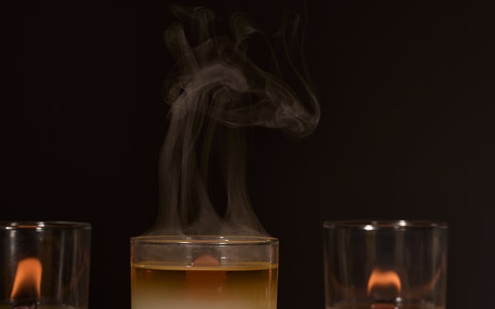 Three candles glowing with a soothing smoke trail against a dark background for a tranquil atmosphere.