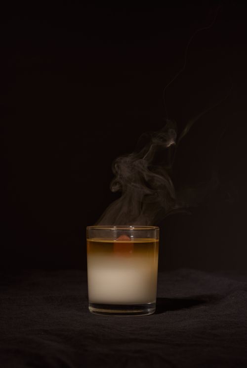 Free Transparent glass holder with aromatic candle with fume for relaxation against dark black background Stock Photo