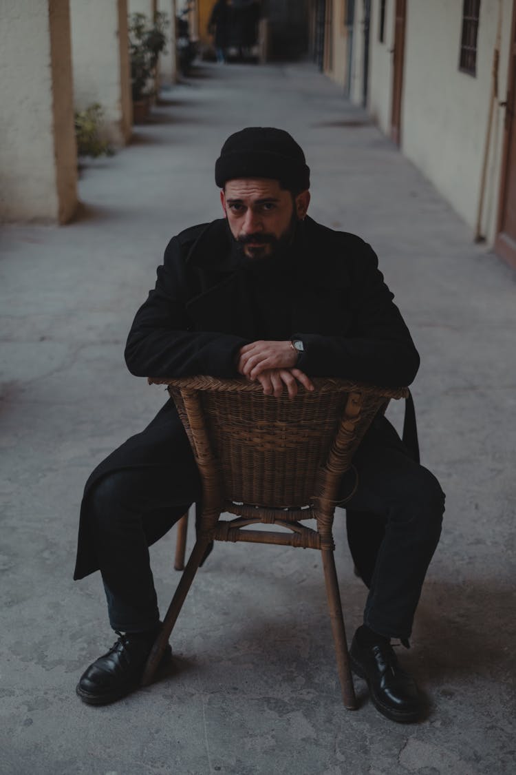 Man In Dark Sitting Backwards On Chair In Corridor