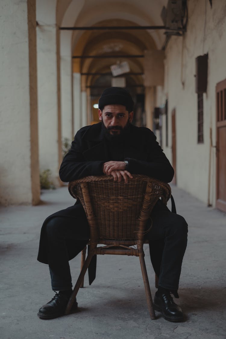 Man Sitting With Spread Legs And Leaning On Chair Back