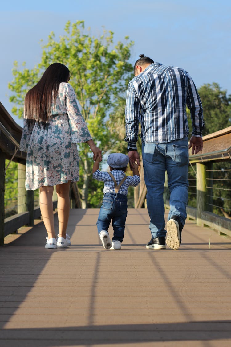 Man And Woman Holding Childs Hand