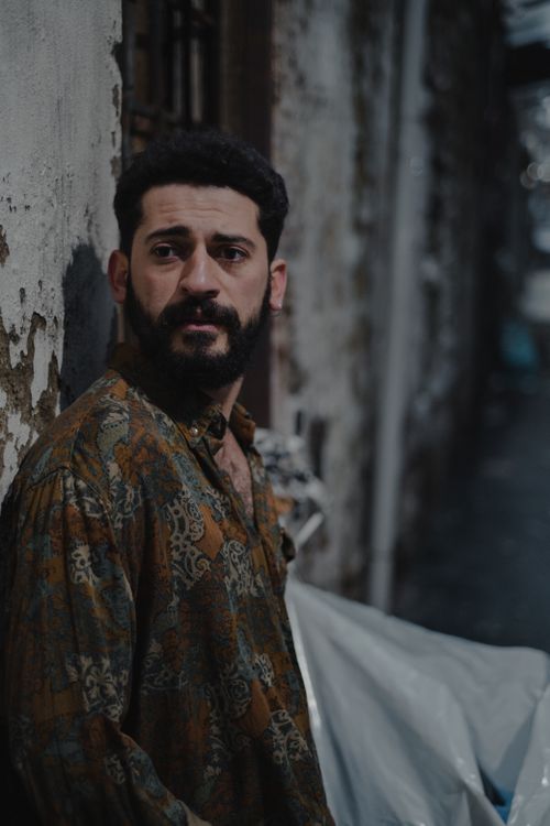 Free Worried ethnic male with beard looking away while leaning on street near shabby wall Stock Photo