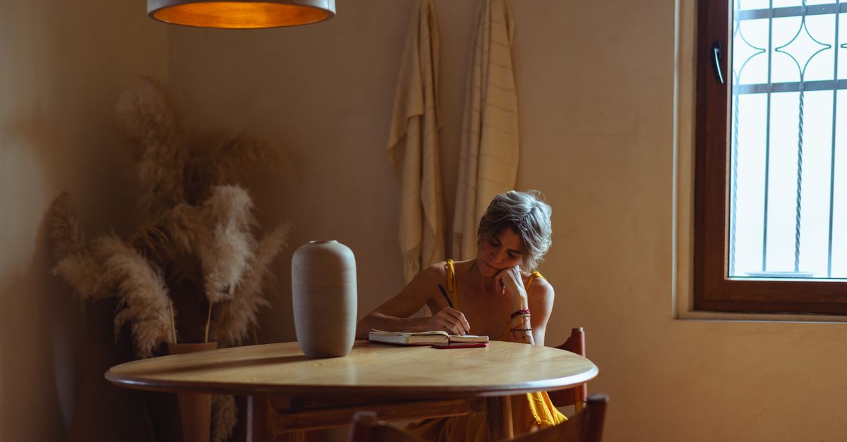 traveler journaling by a window in a minimalist cabin, warm natural light