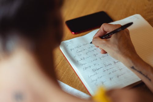 Person Writing on Notebook