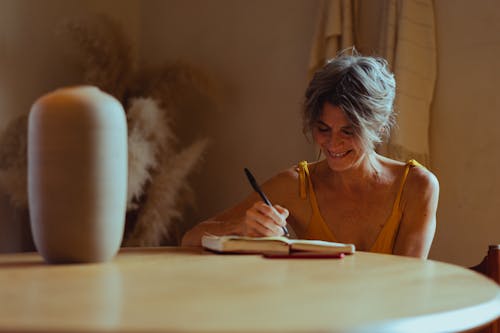 Elderly Woman Writing Her Diary while Smiling
