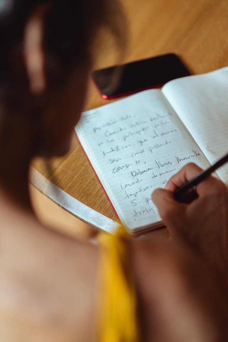 Person Writing On Notebook