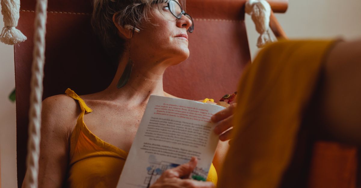 person relaxing in a hostel hammock with a coffee and a book