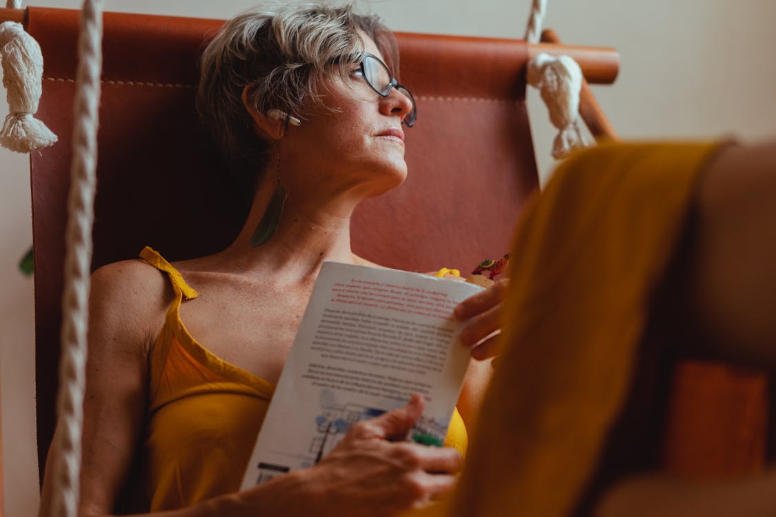 Free Elderly Woman Looking Pensive while Holding a Book Stock Photo