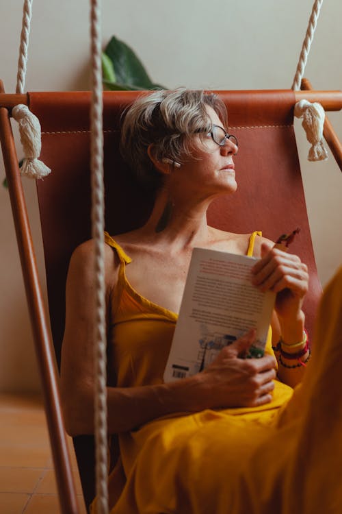 Free Elderly Woman Looking Pensive while Holding a Book Stock Photo