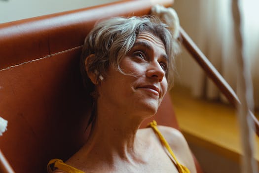 Elderly woman enjoying leisure time indoors, listening to music with wireless earbuds.