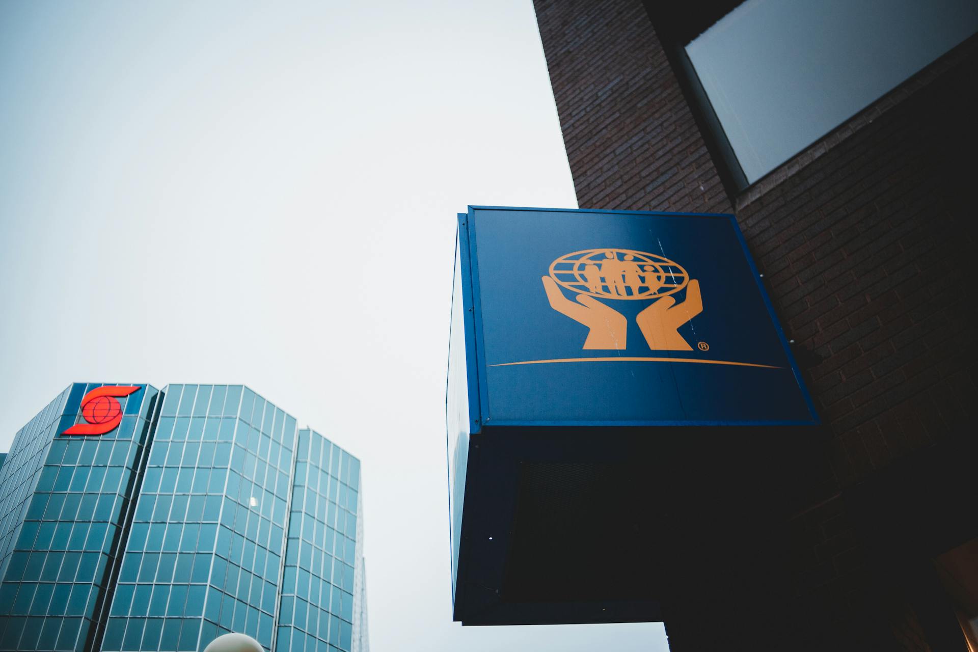 From below of modern financial buildings with logotype on walls against cloudless sky