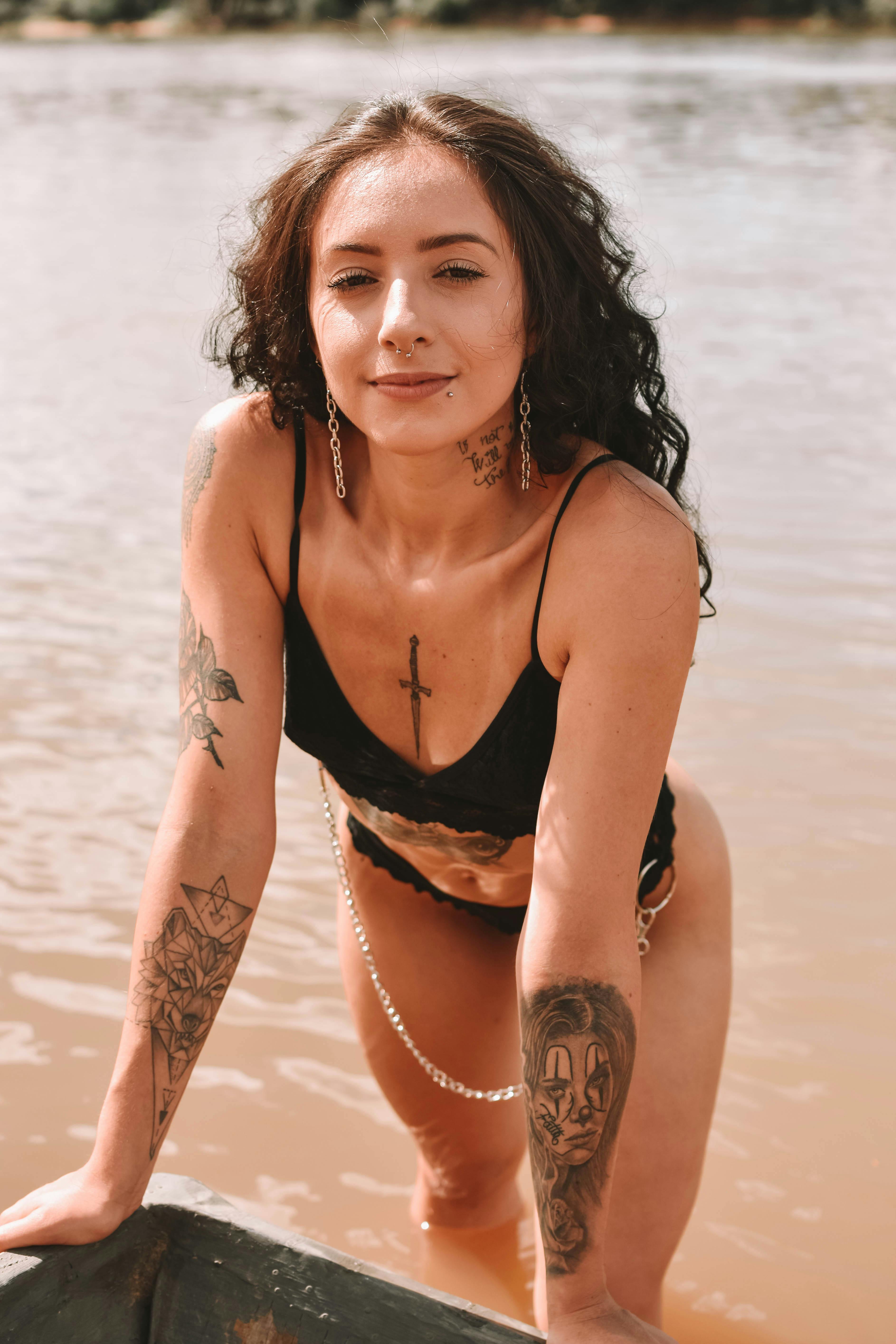 Serious tattooed woman in swimsuit near river Free Stock Photo