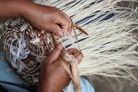 Hands weaving a straw hat, showcasing traditional craftsmanship in Ayangue, Ecuador.