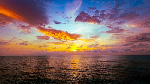 Free Captivating sunset over the ocean with vibrant hues illuminating the sky and water. Stock Photo
