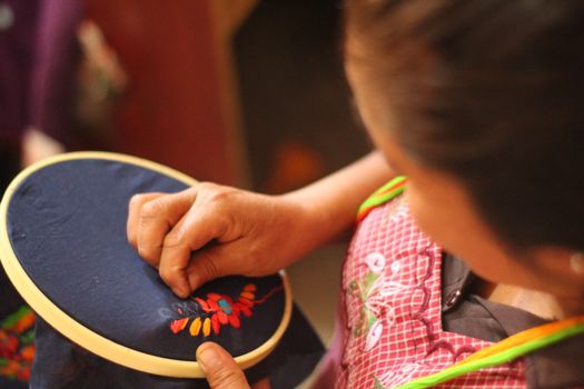 Person Sewing on Blue Textile