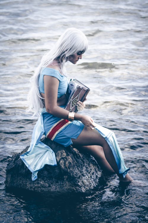 Woman Sitting on Rock in Water