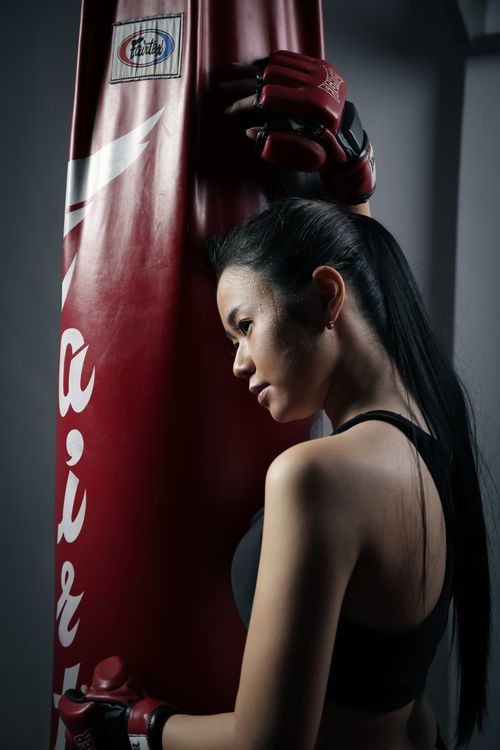 Free An athletic young woman practicing combat sports with a red punching bag indoors. Stock Photo