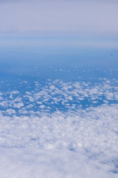 A serene aerial view with fluffy white clouds against a vast blue sky, embodying natural beauty.