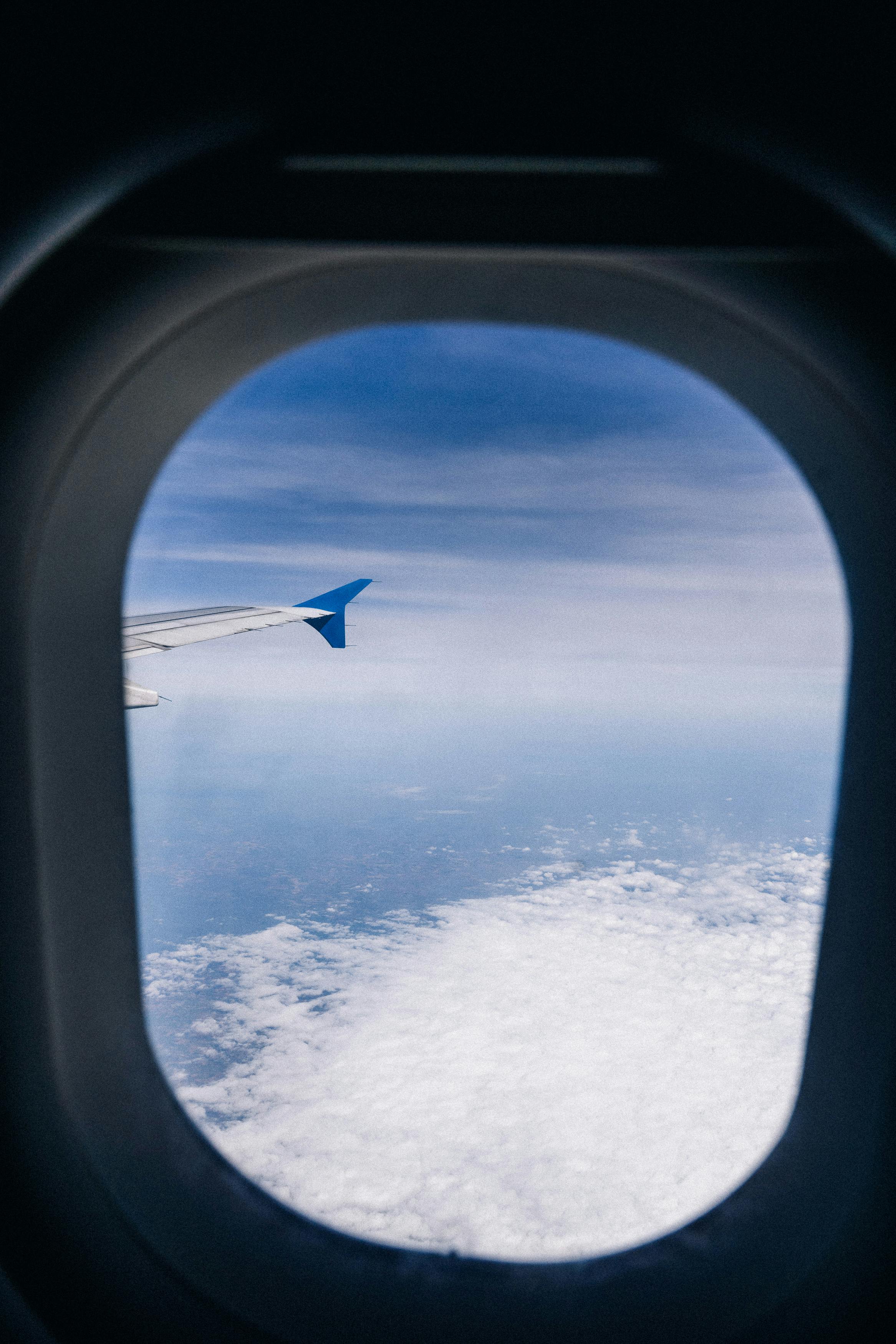 View of clouds and sky from an airplane window, showcasing travel scenery.