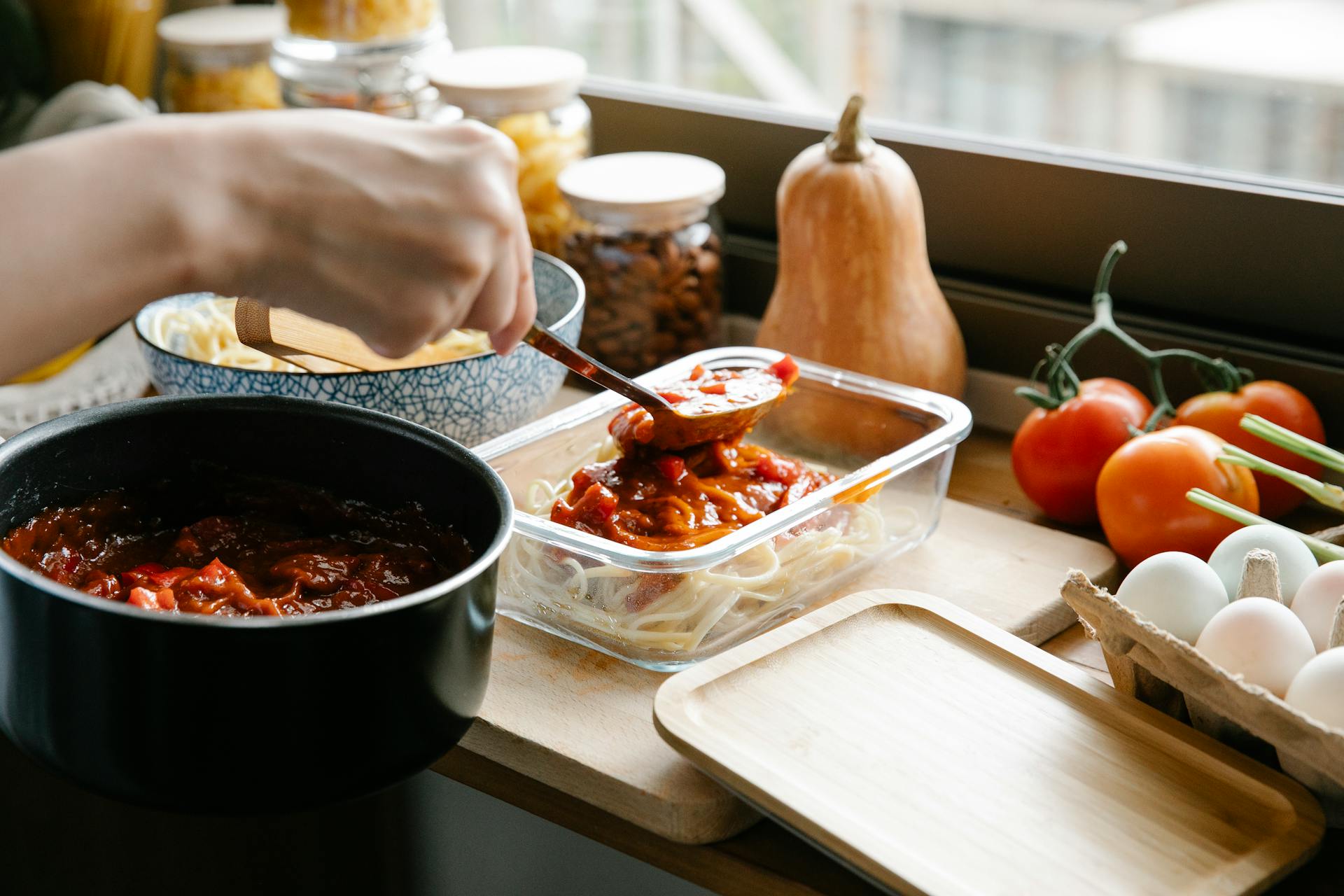 Crop chef pouring bolognese on spaghetti