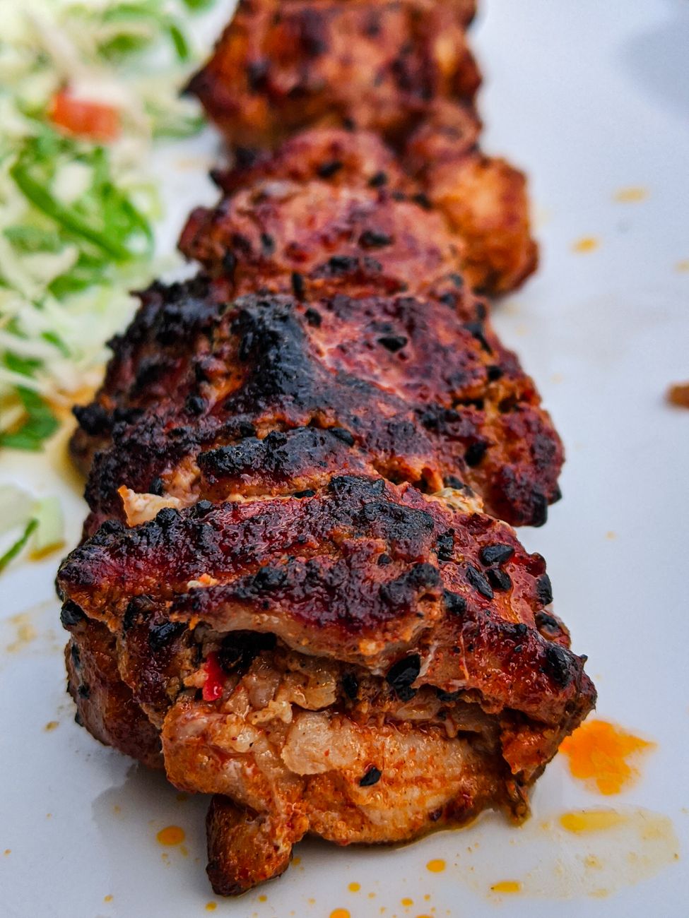 Grilled chicken pieces with dark mahogany berbere spice crust showing charred edges and caramelized seasoning on a white plate
