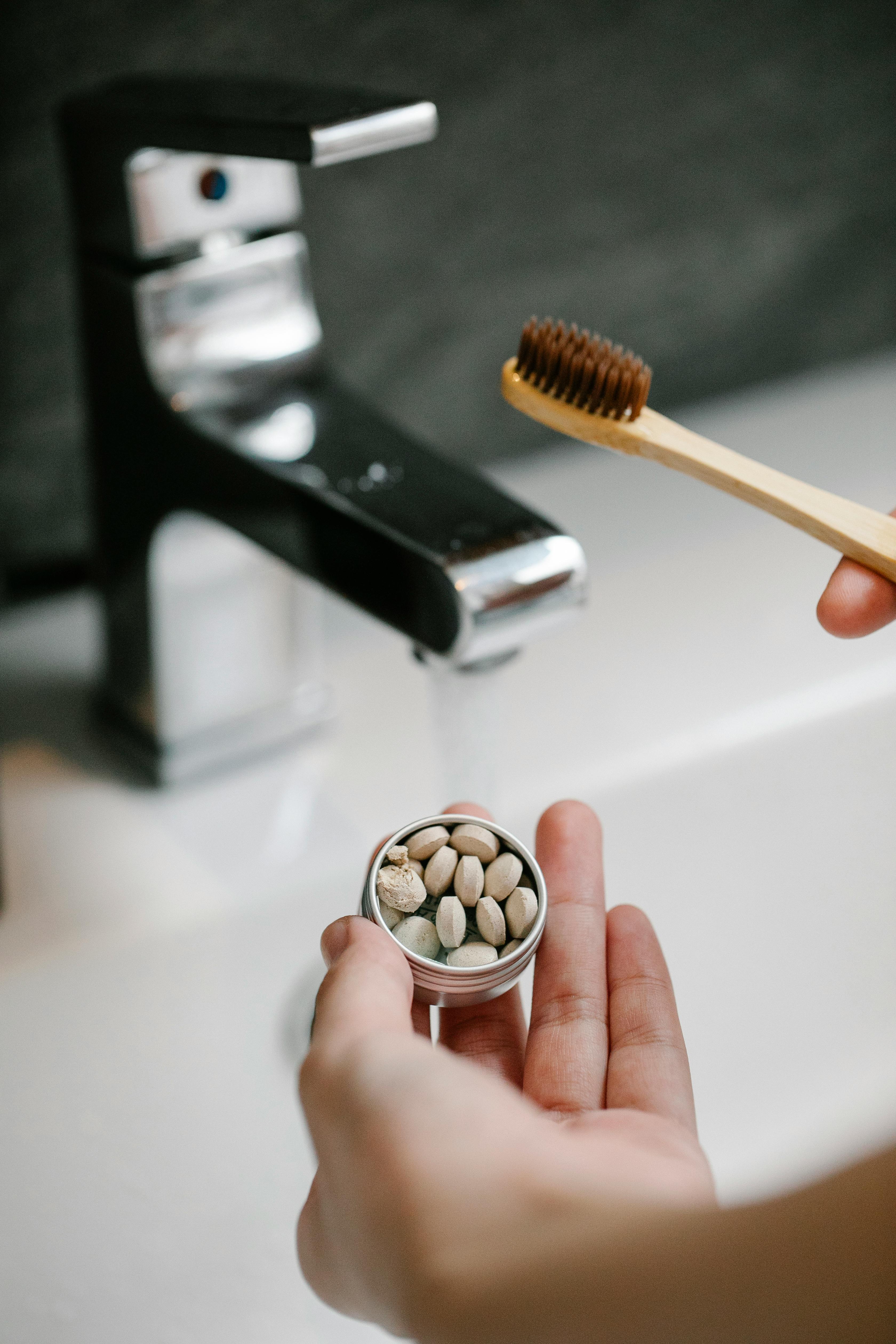 crop woman with toothpaste tablets near sink