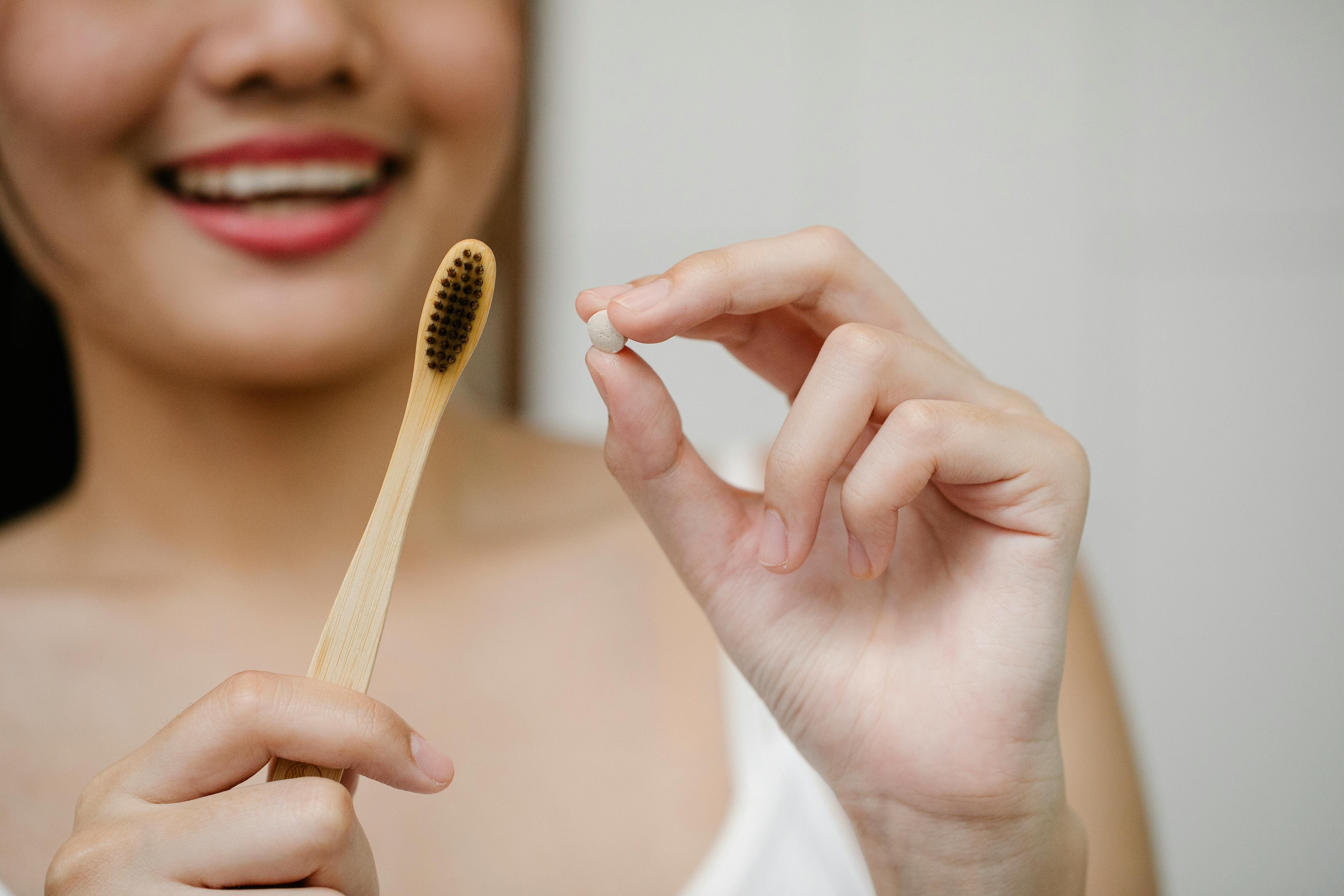 crop woman with toothpaste tablet and toothbrush