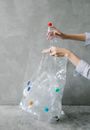 Crop woman putting plastic bottle into bag