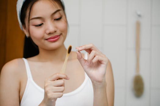 Cheerful Asian woman preparing for oral care routine at home with a bamboo toothbrush.