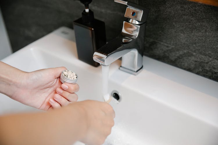 Crop Woman At Sink With Toothbrush And Toothpaste