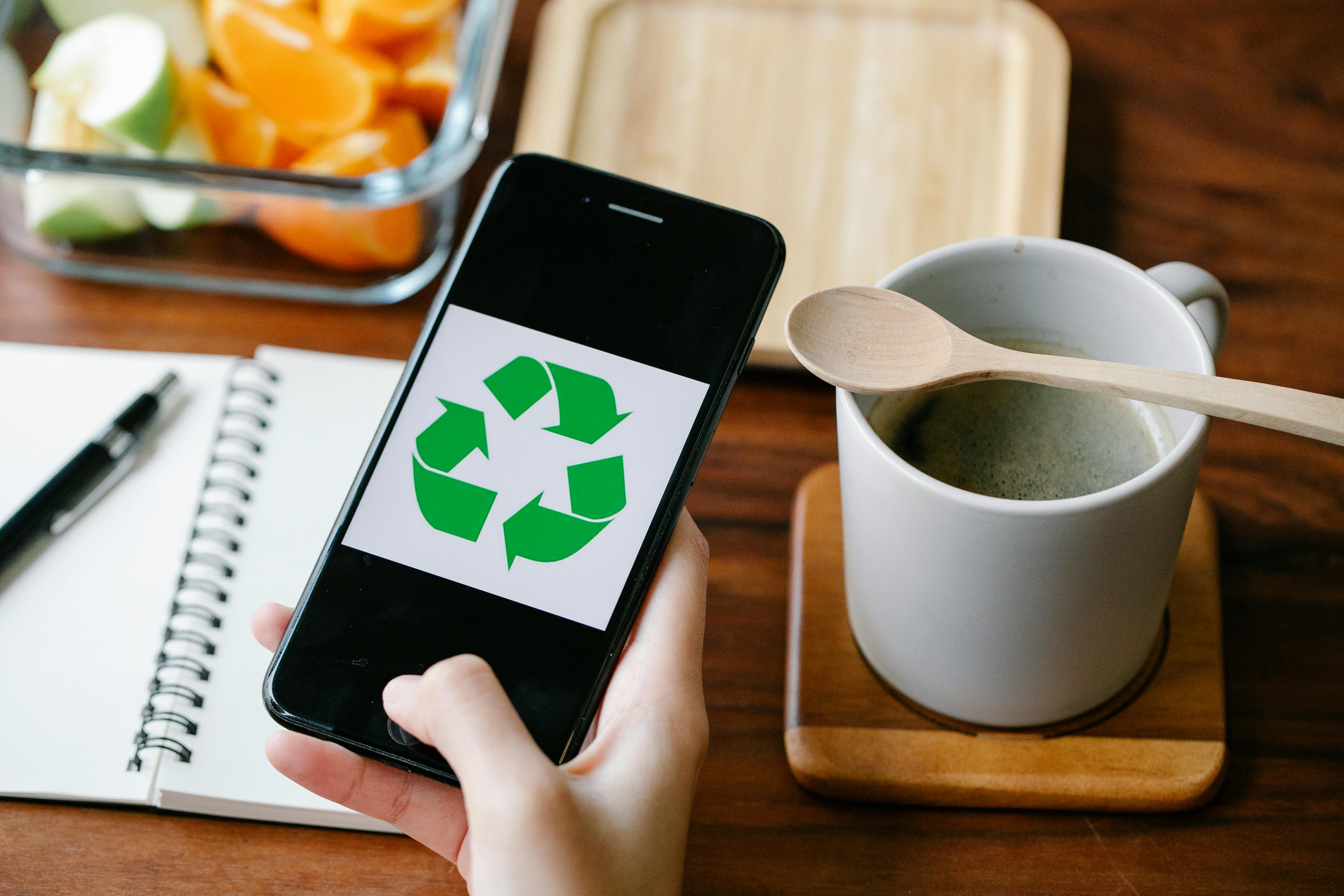 Crop person using recycling app on smartphone against coffee by Sarah  Chai