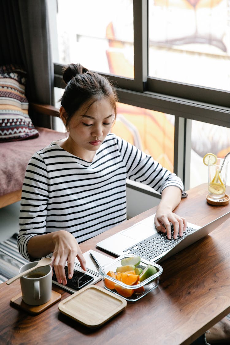 Asian Woman Using Laptop In Cafe