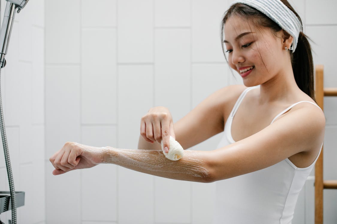 Positive Asian woman washing arm