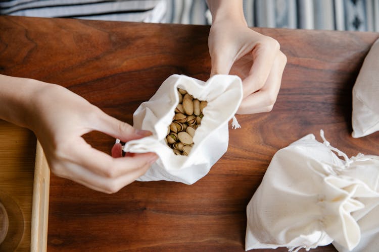 Crop Woman Tying Sack With Pistachios