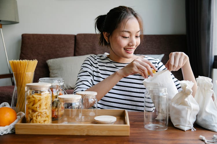 Asian Woman Opening Environmentally Friendly Bag Of Pasta