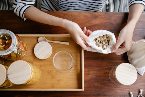 Crop person with bag of pistachios on table